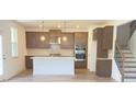 Well-designed kitchen features sleek cabinetry, an island, stainless steel appliances, and nearby stairs at 62 Sheryl Way, Loganville, GA 30052