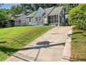 View of the home with a spacious concrete driveway, surrounded by lush greenery at 1649 Beecher Sw St, Atlanta, GA 30310