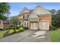 Two car garage features unique stone accents and is complemented by a paved driveway and manicured landscaping at 3250 Seven Oaks Dr, Cumming, GA 30041