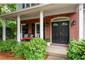 Welcoming front porch with rocking chairs and decorative plants; brick exterior and black door at 206 Kingsley Way, Woodstock, GA 30188