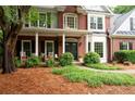 Beautifully landscaped front yard with brick facade and inviting front porch seating at 206 Kingsley Way, Woodstock, GA 30188
