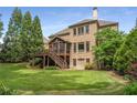 Expansive backyard featuring a screened porch, deck, lush lawn, and mature trees for privacy at 5605 Copper Creek Pass, Cumming, GA 30040