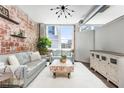 Bright living room with exposed brick, modern lighting, seating, and large windows with city views at 800 Peachtree Ne St # 8531, Atlanta, GA 30308