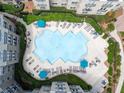 Aerial view of community pool with lounge chairs, umbrellas, lush landscaping, and multiple residential buildings at 800 Peachtree Ne St # 8531, Atlanta, GA 30308