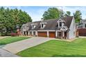 Corner view of a beautiful home featuring a lush lawn, 3-car garage, and side entrance at 150 South St, Buford, GA 30518