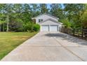 Inviting two-story home featuring a long driveway and a two-car garage nestled among mature trees at 75 Auburn Rd, Auburn, GA 30011