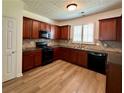 Cozy kitchen featuring wooden cabinets, black appliances, tile backsplash, and wood-look flooring at 234 Silver Arrow Cir, Austell, GA 30168