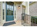 Elegant front door of a brick home, framed by classic stonework and manicured greenery at 223 Falling Water Way, Woodstock, GA 30188