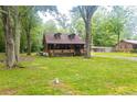 Log cabin featuring dormer windows and inviting front porch surrounded by a green lawn and trees at 218 Green Acre Ln, Cartersville, GA 30121