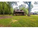 A well-maintained log cabin with a covered porch, nestled among mature trees on a grassy lot at 218 Green Acre Ln, Cartersville, GA 30121