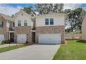 Charming townhome featuring a brick facade, white siding, and an attached one-car garage at 389 Navigator Ln, Mcdonough, GA 30253