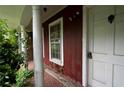 Close-up of front porch with white door and aged brickwork, enveloped by lush greenery at 1395 Clay Sw Rd, Mableton, GA 30126