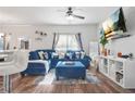 Bright living room featuring a blue sectional, ceiling fan, and decorative shelving at 3143 Bonnes Dr, Stonecrest, GA 30038