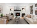 Bright living room featuring a modern fireplace, mantle, and neutral-toned furnishings at 7000 Woodland Nw Pl, Kennesaw, GA 30152