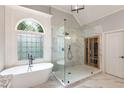 Elegant bathroom featuring a soaking tub, glass-enclosed shower, and a large window with decorative glass at 5173 Brendlynn Dr, Suwanee, GA 30024