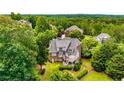 Back of large brick home is surrounded by lush greenery, with a spacious deck and mature trees at 5173 Brendlynn Dr, Suwanee, GA 30024