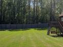 Spacious backyard with green grass, a wooded backdrop, and a play structure at 1952 Azalea Dr, Lawrenceville, GA 30043