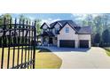 Beautiful two-story home featuring an attached two-car garage, a paved driveway, and a black iron security gate at 1952 Azalea Dr, Lawrenceville, GA 30043