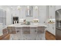 Bright kitchen with white cabinets, stainless steel appliances, quartz countertops and pendant lighting over the island at 124 Everley Walk, Alpharetta, GA 30009
