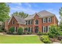 Traditional two-story brick home with manicured lawn, landscaping and basketball hoop in driveway at 9595 Rod Rd, Alpharetta, GA 30022