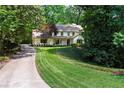 A well-maintained house with a manicured lawn and a concrete driveway, surrounded by mature trees at 4219 Harrogate Nw Dr, Atlanta, GA 30327