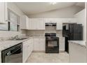 Well-lit kitchen featuring white cabinets, granite counters, and modern black appliances at 4905 Sandberg Ct, Stone Mountain, GA 30088