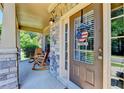 Inviting front porch with stone accents, wood rocking chairs, and a patriotic door decoration at 3975 Silverthorn Trce, Cumming, GA 30028