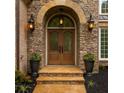 Elegant stone entrance featuring a beautifully crafted wood door and decorative sconces at 5705 Registry Oaks Se Ln, Mableton, GA 30126