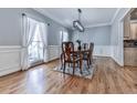 Formal dining room with wainscoting, hardwood floors, and stylish lighting with a view to the exterior at 5090 Eubanks Rd, Woodstock, GA 30188