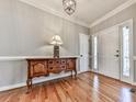 Elegant foyer with hardwood floors, white trim, and a stylish console table illuminated by a decorative table lamp at 5090 Eubanks Rd, Woodstock, GA 30188