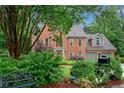 Beautiful brick house with lush front yard landscaping, a bench and a two-car garage at 3915 Woolbridge Way, Marietta, GA 30062
