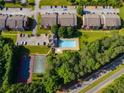 Aerial view showcasing community amenities, including a pool, tennis court, and surrounding lush trees and buildings at 7712 Autry Cir # 701, Douglasville, GA 30134