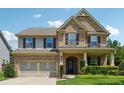 Charming two-story brick home featuring an attached two-car garage, manicured lawn and covered front porch at 4090 Danbury Farms Dr, Cumming, GA 30040