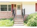 A welcoming front door is accessed by brick steps and framed by red shutters and lush greenery at 2614 Princess Se Ln, Marietta, GA 30067
