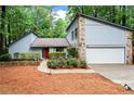 A well-maintained home with stone details, a red door, beautiful landscaping, and an attached garage at 895 Fawn Way, Marietta, GA 30068