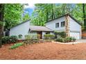 This home features a stone chimney, attached garage, landscaped front yard, and is surrounded by mature trees at 895 Fawn Way, Marietta, GA 30068