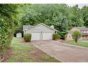 View of the home and its two-car garage nestled in a wooded lot and green yard at 3960 Rocmar Dr, Snellville, GA 30039