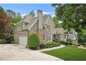 Exterior home with beautiful landscaping and driveway; also including partial view of side-entry two-car garage at 702 Crescent Cir, Canton, GA 30115