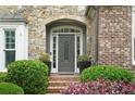 Charming front door with sidelights, decorative glass, and manicured landscaping at 702 Crescent Cir, Canton, GA 30115