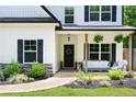 Close-up of the home's front porch, featuring a comfortable seating area, decorative plants, and stylish black door at 1417 Woodrow Kay Rd, Rockmart, GA 30153