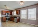 Spacious kitchen boasts stainless steel appliances, wood cabinetry, and tile floors at 6684 Crane Ave, Fairburn, GA 30213