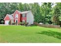 A view of the well-manicured lawn and tree-lined backyard behind this charming two-story home at 630 Beckenham Walk Dr, Dacula, GA 30019