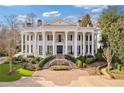 Stately home featuring a grand entrance with symmetrical staircases, manicured gardens, and impressive architectural details at 3977 Sweet Bottom Dr, Duluth, GA 30096