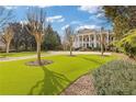 Lush front lawn with scattered trees offering a partial view of a grand home with classic architectural features at 3977 Sweet Bottom Dr, Duluth, GA 30096