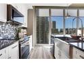 Contemporary kitchen featuring granite countertops, farmhouse sink, and city views through expansive windows at 855 Peachtree Ne St # 1703, Atlanta, GA 30308