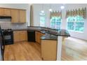 Well-lit kitchen with wooden cabinets, granite countertops, stainless steel appliances, and hardwood floors at 430 English Ivy Way, Woodstock, GA 30188