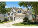 View of the two-story home featuring blue shutters, a two-car garage, and mature trees at 795 Creek Glen Rd, Mableton, GA 30126