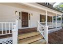 Close up of a classic front porch with white railings, wooden flooring, and a sturdy wooden front door at 4166 Riverhill Ne Ct, Roswell, GA 30075