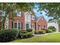 Charming two-story brick home with manicured lawn, mature landscaping, and large windows at 2330 Springmonte Pl, Cumming, GA 30041