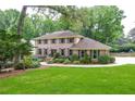 Traditional brick home featuring a manicured lawn, mature trees, and a meticulously maintained garden at 4366 Cedar Wood Sw Dr, Lilburn, GA 30047